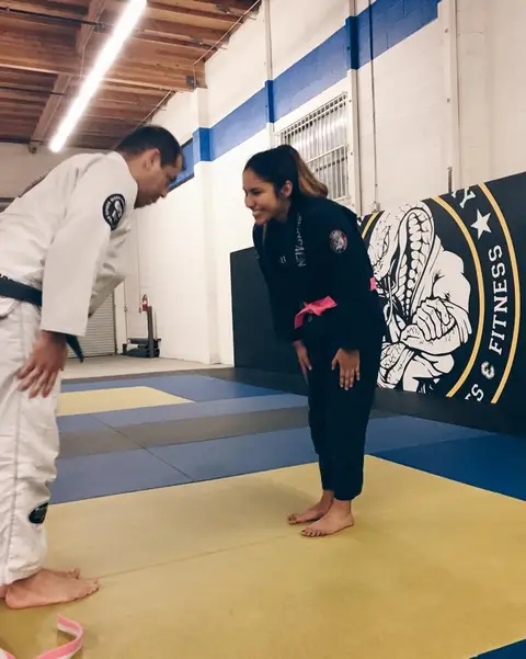 A coach and a student bowing to each other on the mat