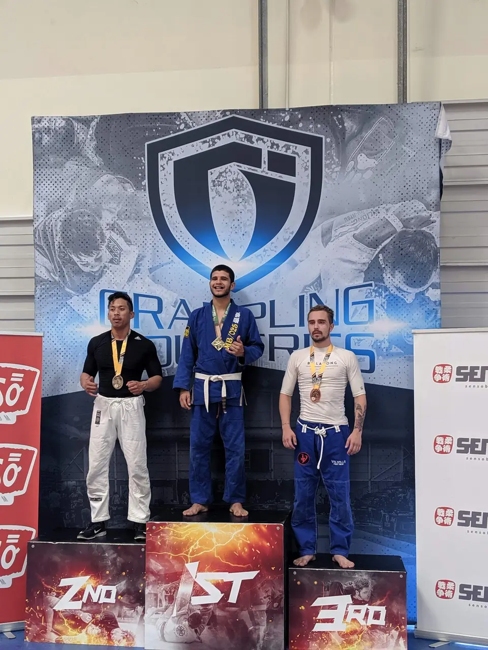 Athletes wearing medals on the podium at a grappling tournament
