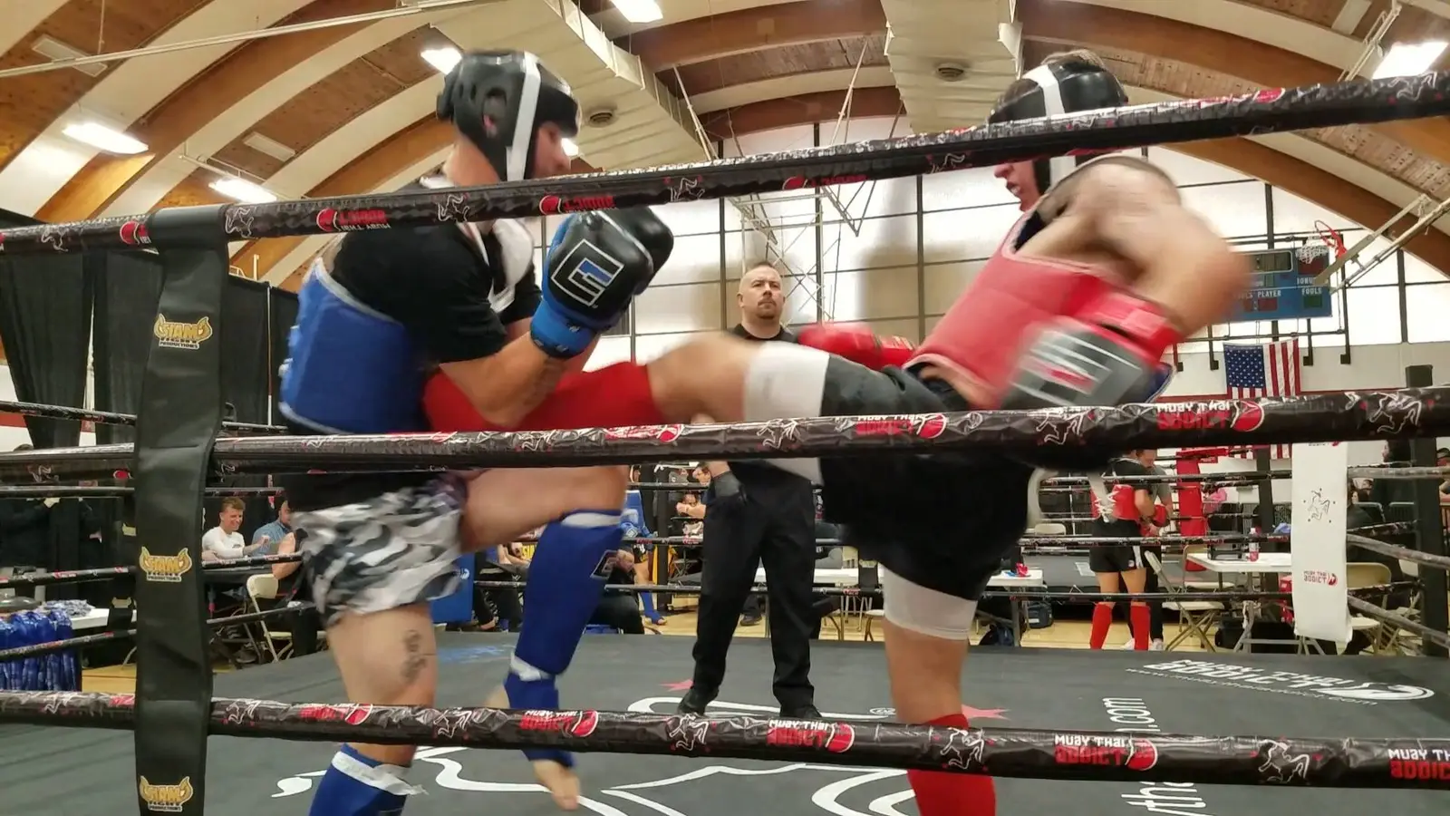 Two fighters in protective gear competing in a ring while a referee watches